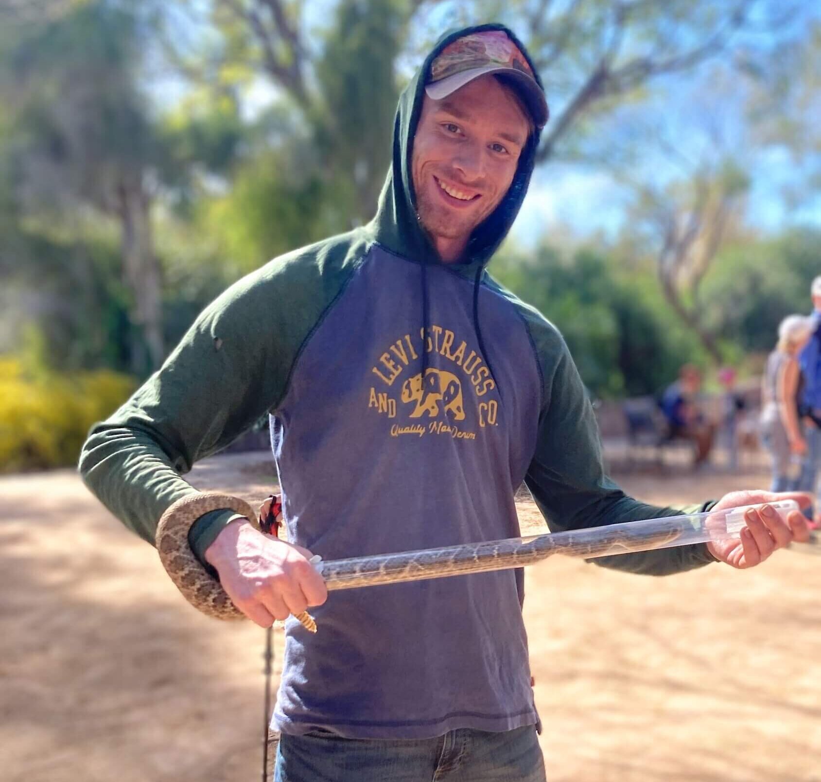 Researcher Jake Lee holding a western diamond-backed rattle snake at Boyce Thompson Arboretum.